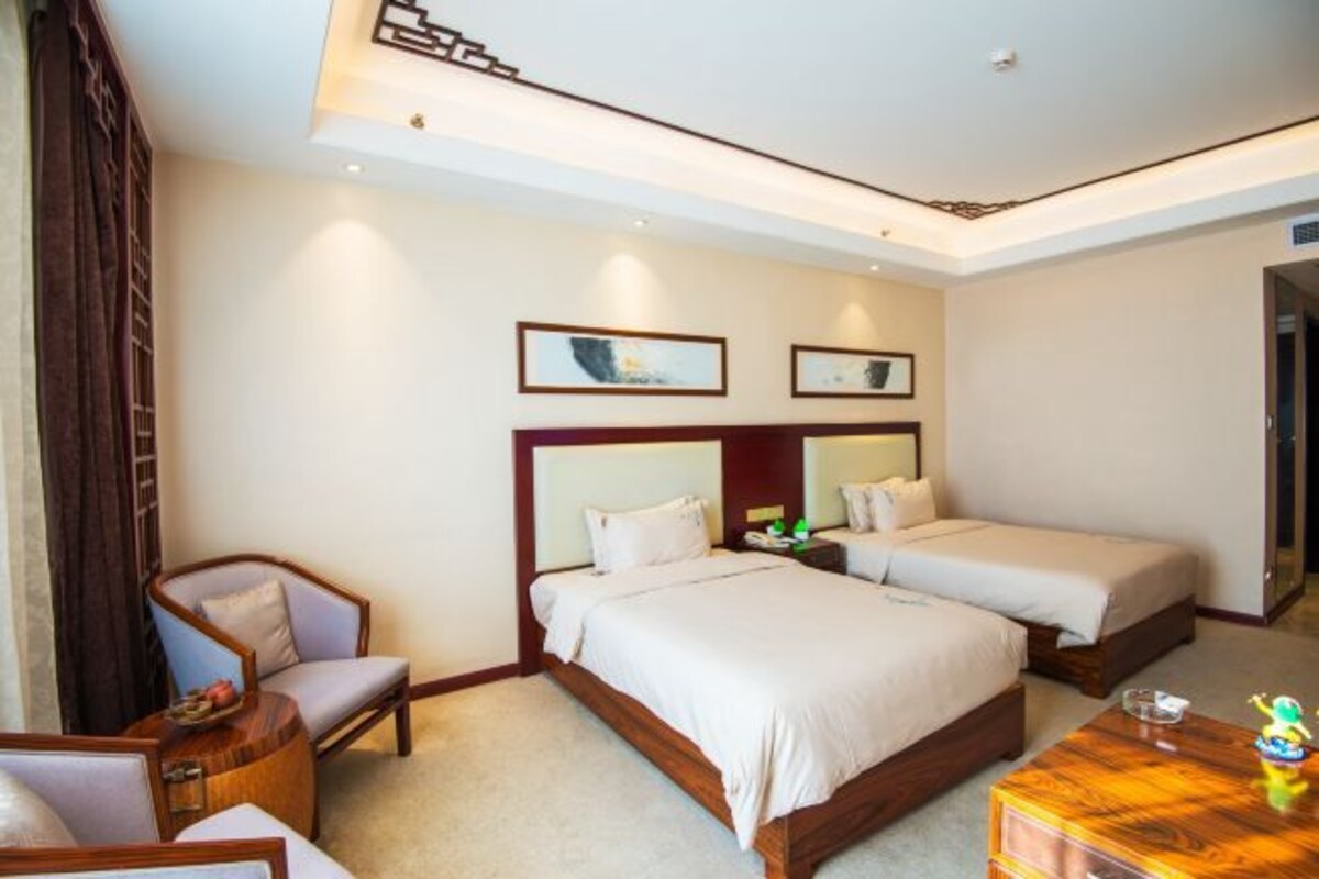 Une chambre d’hôtel avec un lit, une chaise, une petite table et des œuvres d’art accrochées au mur.