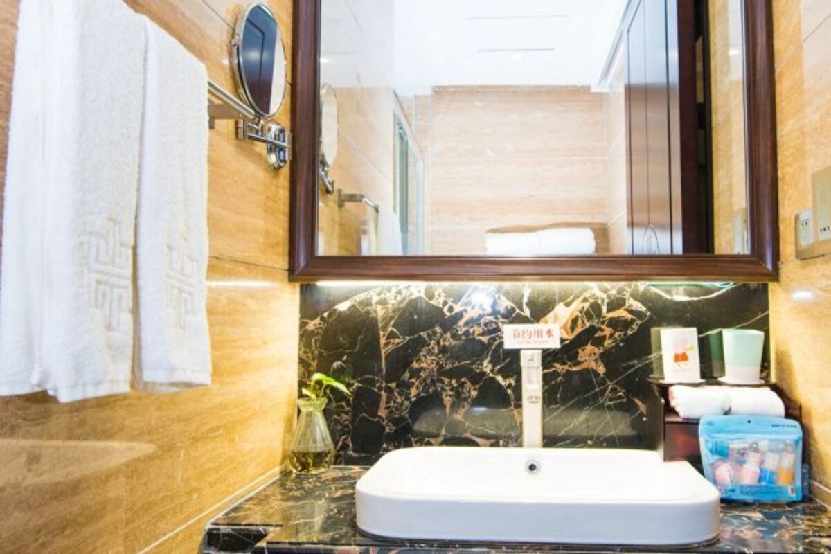 Une salle de bain avec un lavabo en marbre, un miroir et un porte-serviettes.