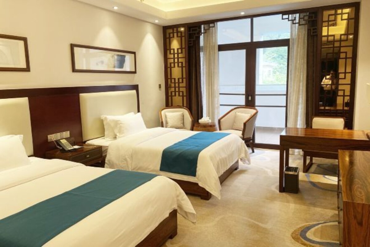 Une chambre d’hôtel avec deux lits, un bureau et une chaise.