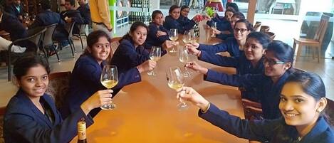 A group of people seated around a table in a restaurant with wine glasses, a bottle of wine, and a menu visible.