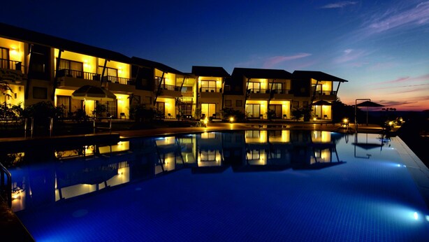 A hotel with a swimming pool, multiple balconies, and well-lit exterior. - Regenta Resort Soma Vine Village (Nashik)