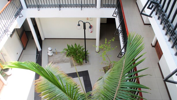 A multi-level atrium with a tiled floor, a central column, and potted plants. - Hotel Samaña (Arica)