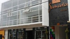 A modern building with a glass facade and a storefront with the name 'Samaria'. - Hotel Samaña (Arica)