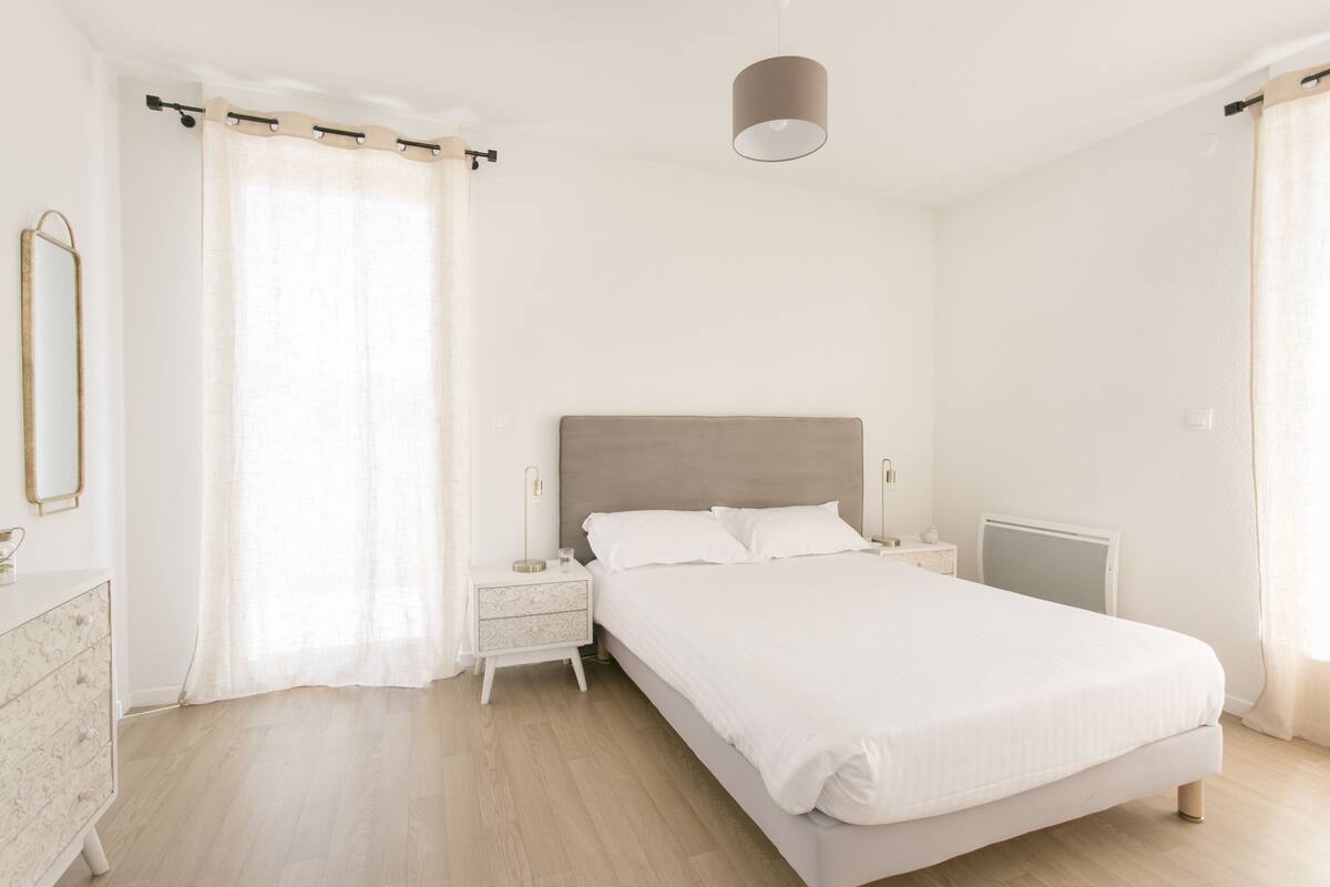 Een slaapkamer met een groot bed, een nachtkastje, een kaptafel en een spiegel.