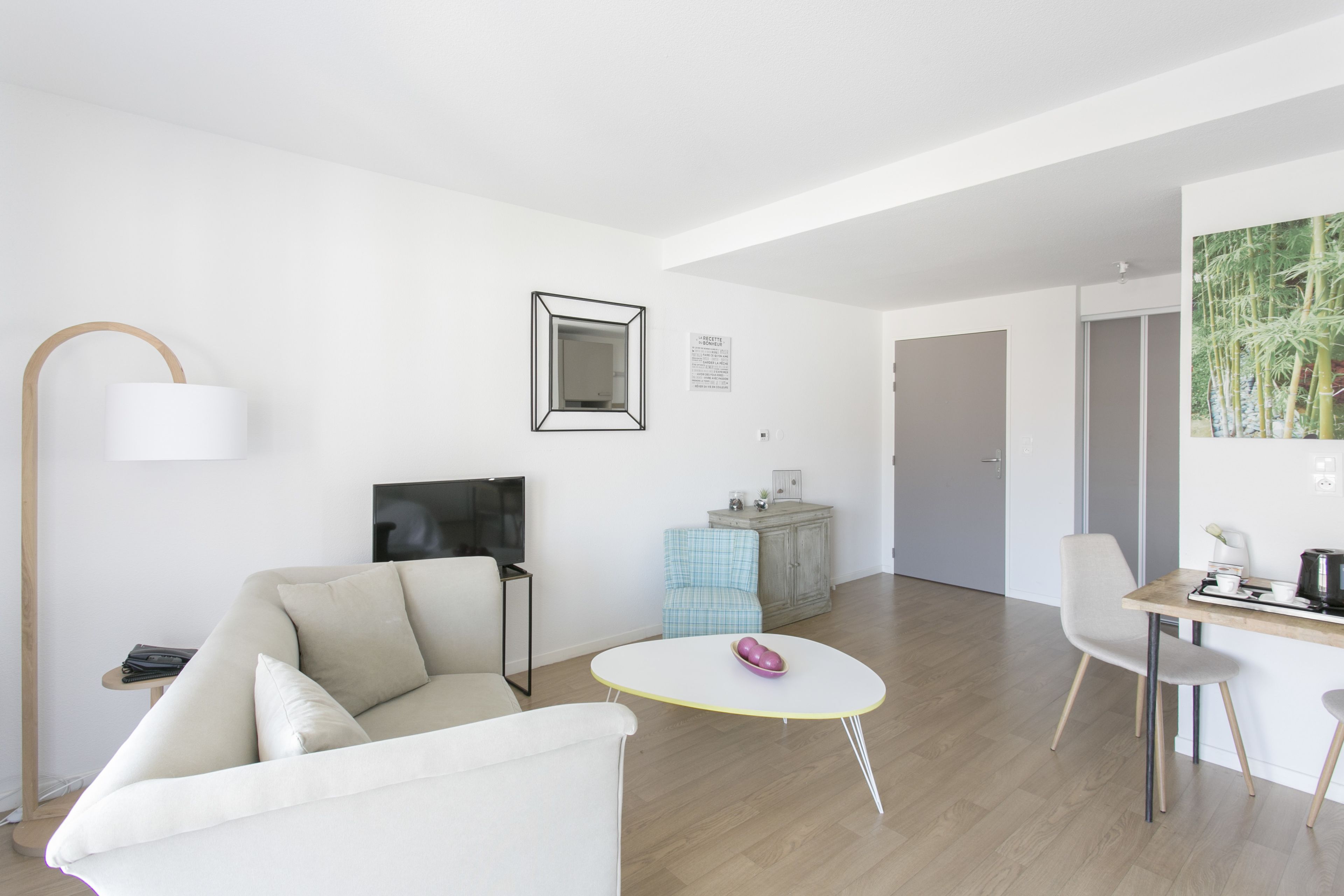 En moderne stue med sofa, et rundt bord, fjernsyn, et skab og en stol.
