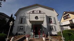 Un hotel con fachada blanca, entrada roja y un letrero que dice "WALDERBURG HOTEL".
