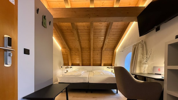 Un dormitorio moderno con techo inclinado, una cama, un escritorio y una silla.