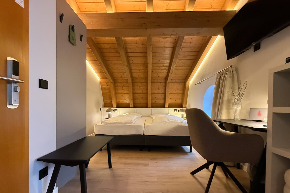 Un dormitorio moderno con techo inclinado, una cama, un escritorio y una silla.
