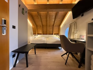 A modern bedroom with a sloped ceiling, a bed, a desk, and a chair. - Hotel Villa Waldperlach (Munich)