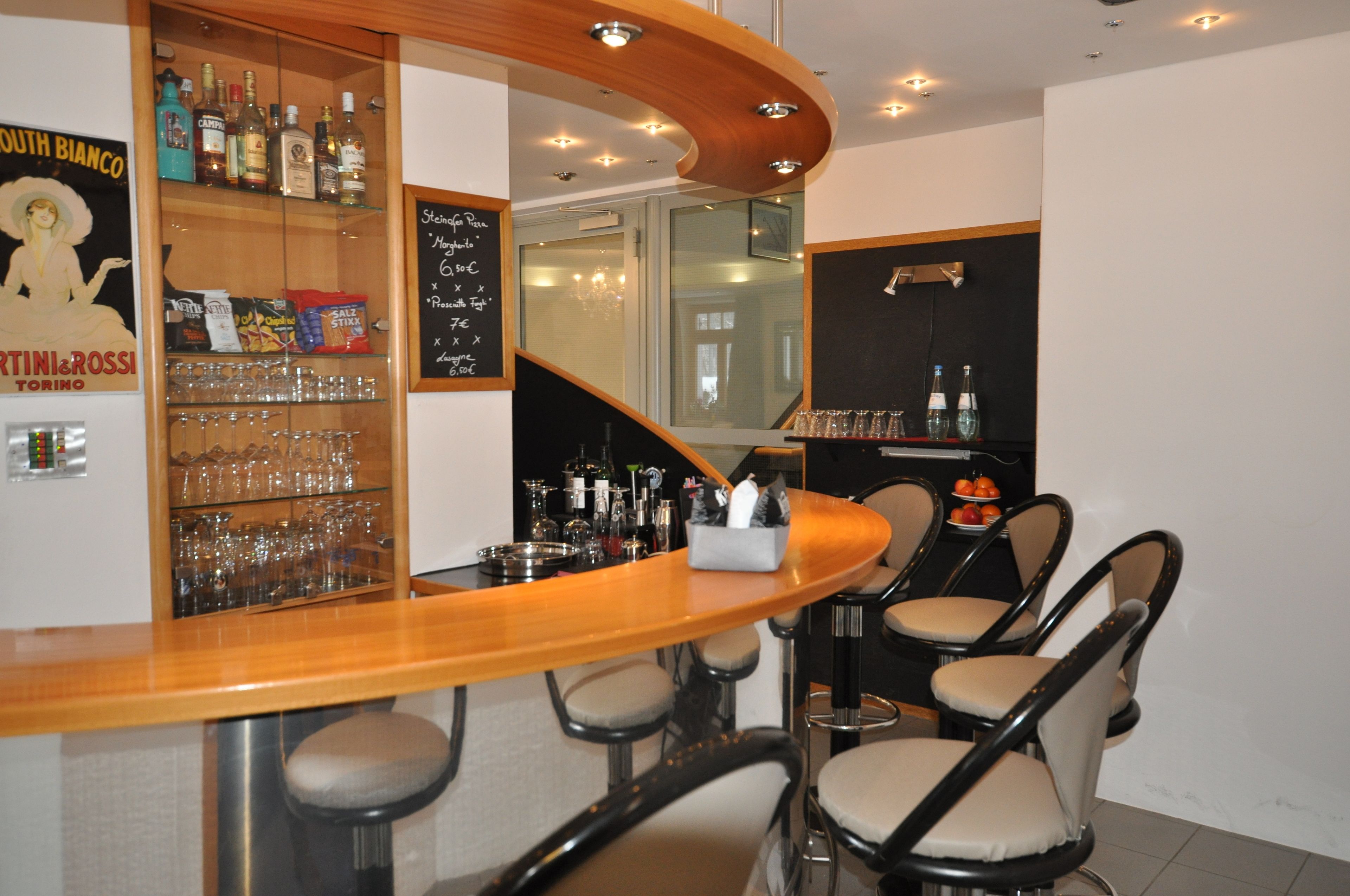 A bar area with a wooden counter, bar stools, and a glass display case with bottles and glasses.