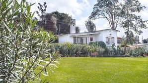 A white house with a well-maintained lawn and a bench in the yard. - Methodist Resort (Nairobi)