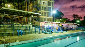 A swimming pool area with a covered seating area, a building with multiple floors, and a staircase leading to an upper level. - Methodist Resort (Nairobi)