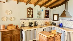 Una cocina rústica con vigas de madera, un revoque de azulejos y diversos electrodomésticos.