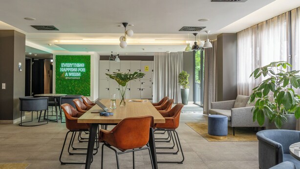 Une salle de conférence moderne, dotée d’une longue table, de fauteuils en cuir et d’une grande plante en pot.