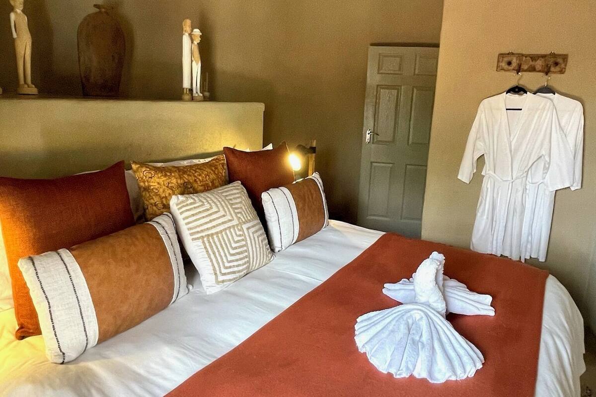 Une chambre d’hôtel avec un lit, des oreillers, un peignoir et une porte.