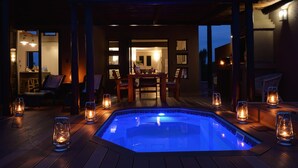 Ein Whirlpool, umgeben von einer Holzterrasse, mit Laternen und einem Essbereich im Hintergrund.
