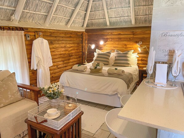 A cozy room with a wooden ceiling, a bed with white bedding, a bedside table with a tray, and a wall with a motivational quote.
