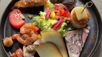 Un plato de comida con diferentes elementos, incluyendo algo a la parrilla, un trozo de carne, verduras y una loncha de queso.
