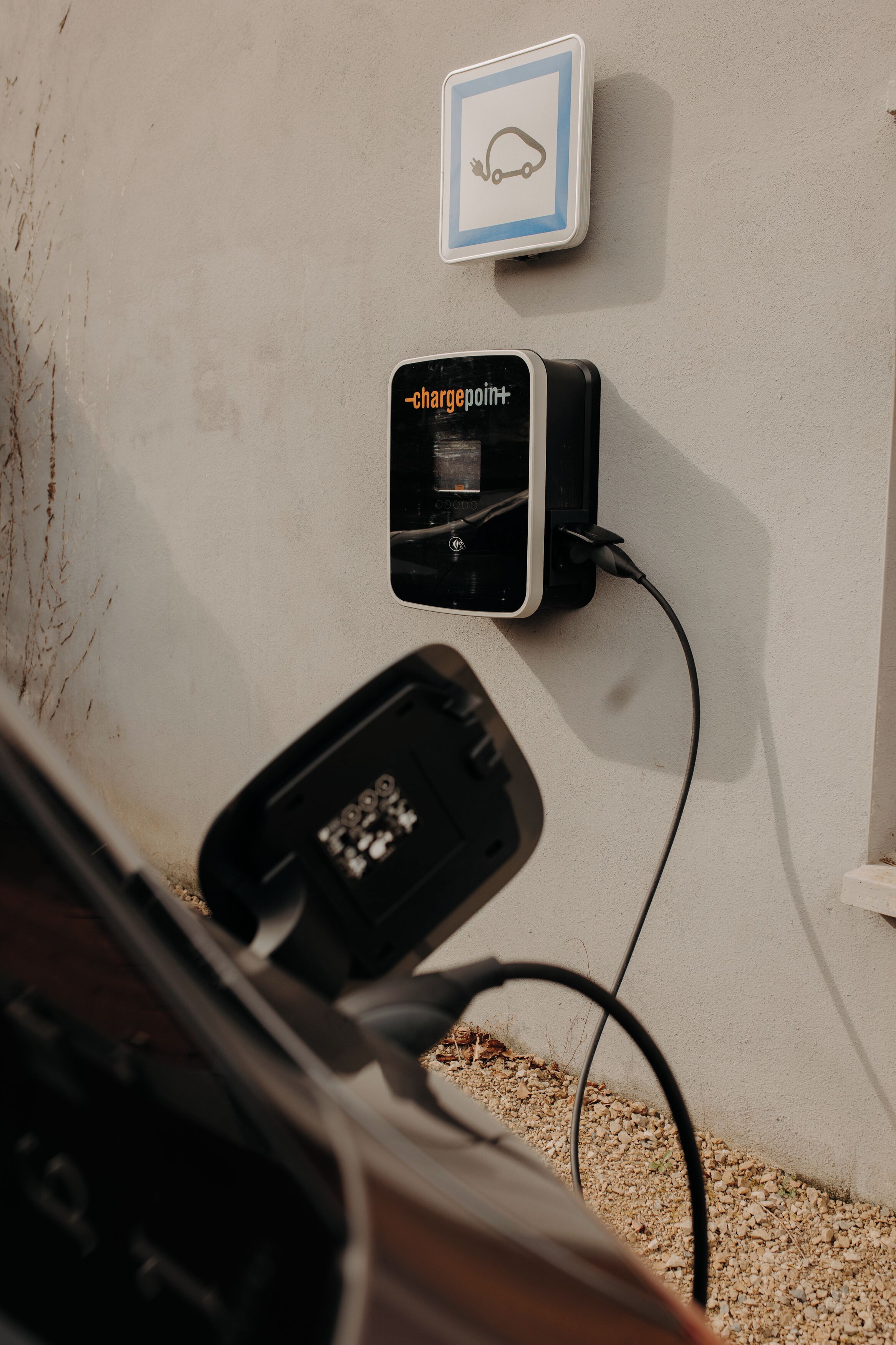 A wall-mounted charging station with a car icon sign above it.