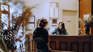 A reception desk with a wooden counter, a bulletin board, and a potted plant. - Logis Hôtel du Parc (Cransac)