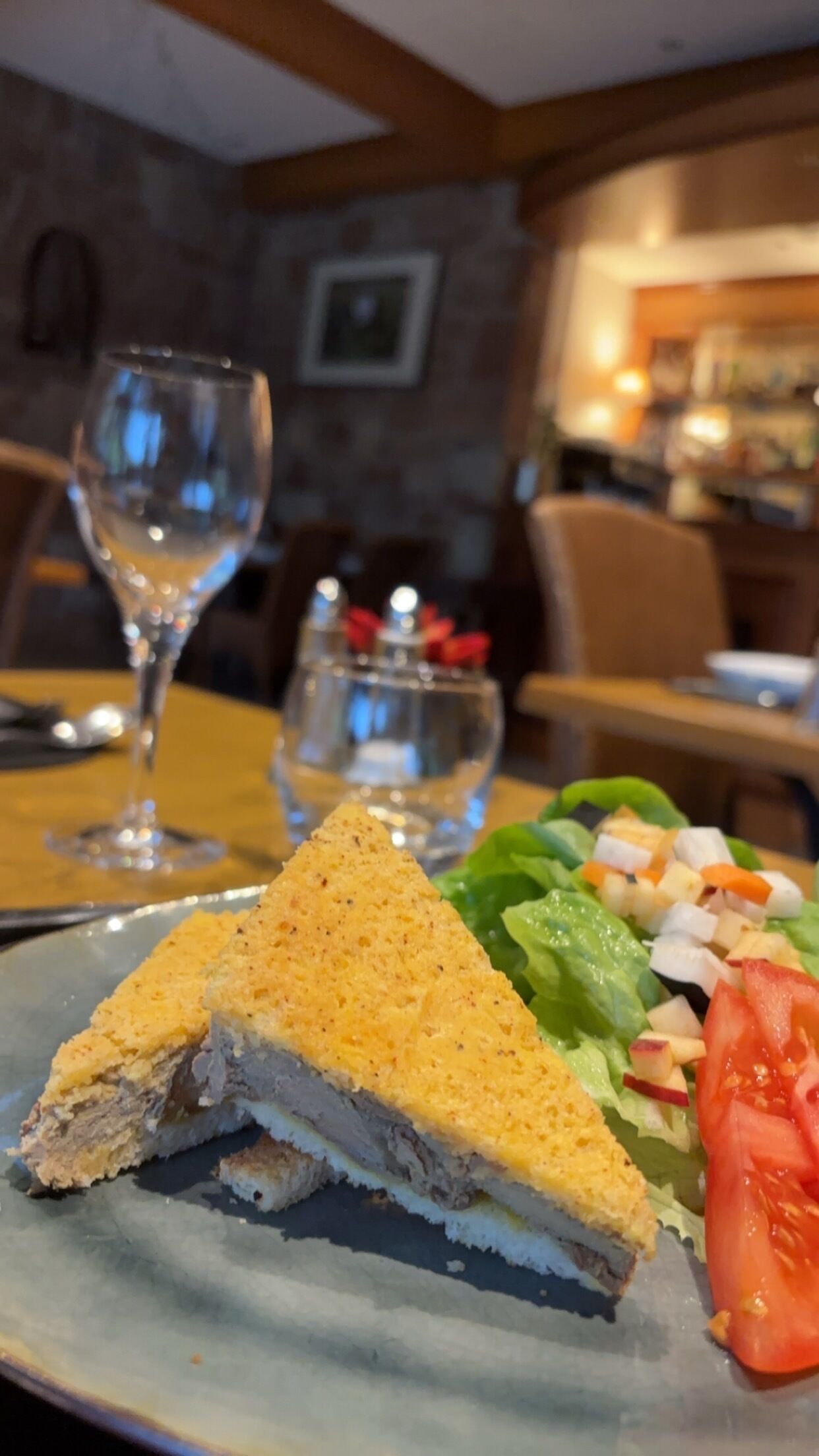 A plate with a sandwich, a glass of water, and a salad.
