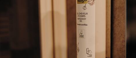 A bathroom with a white bottle of Logis hair and body gel mounted on a wall.