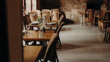 A restaurant with wooden tables and chairs, stone walls, and hanging plants.