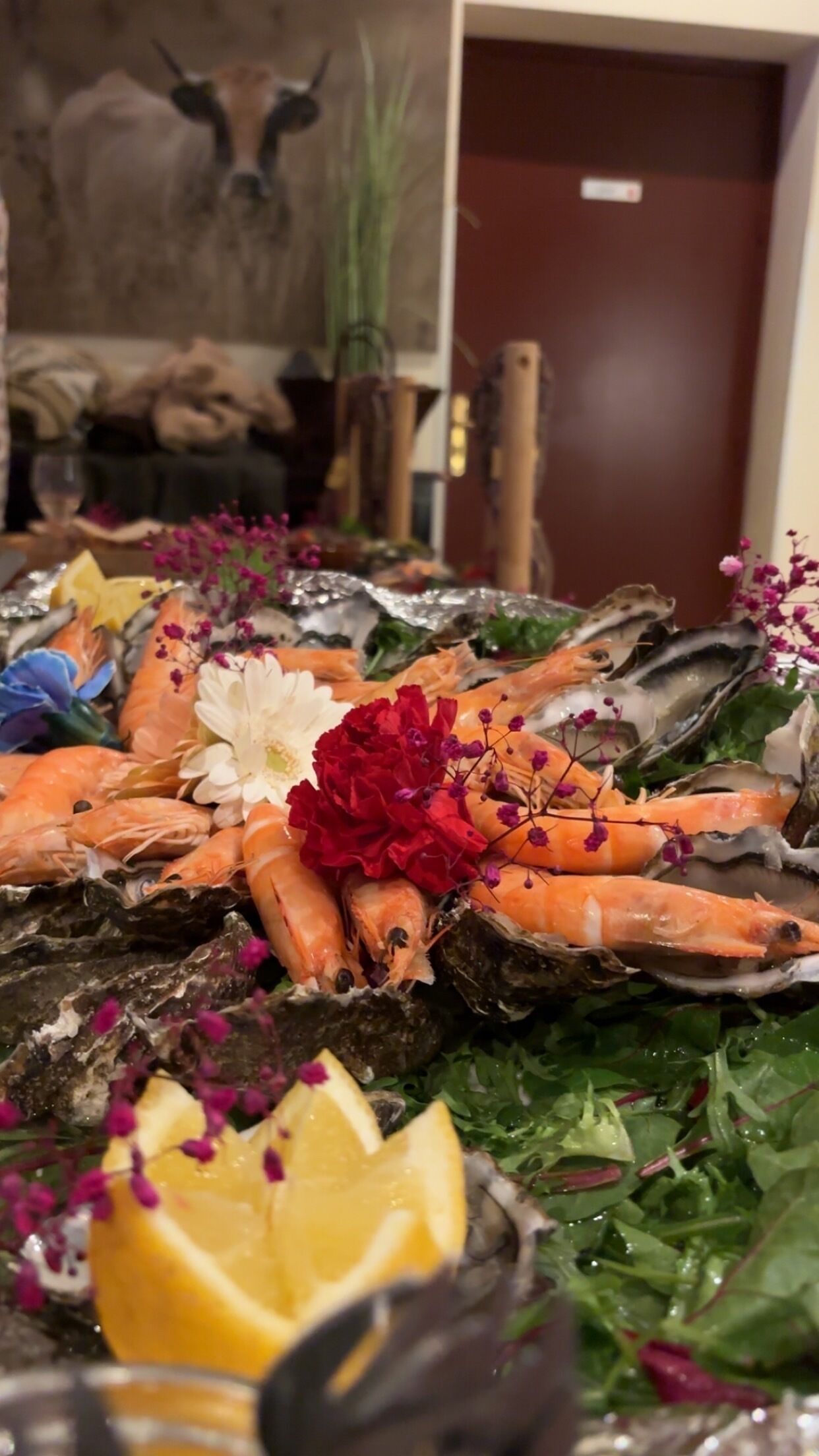 A seafood platter with shrimp, oysters, and garnishes on a bed of greens.