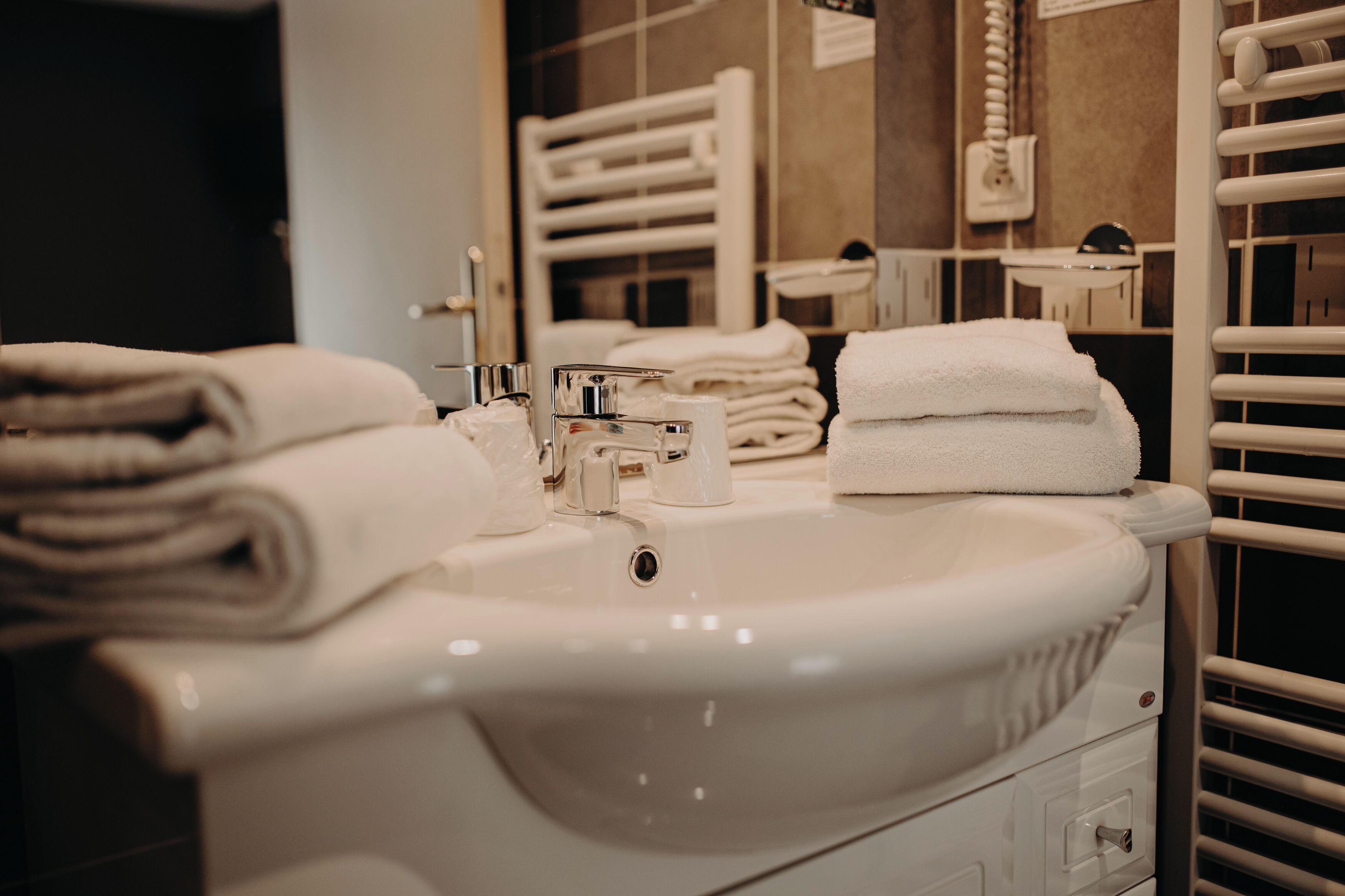 A bathroom with a sink, towel stack, and a mirror.