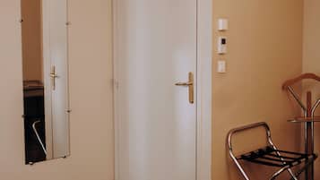 Quarto de hotel com cama, espelho, porta e ar condicionado.