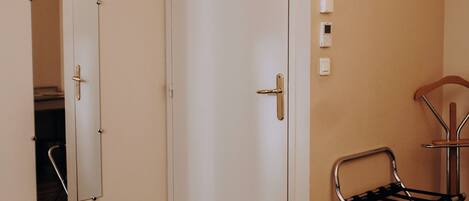 Una habitación de hotel con cama, espejo, puerta y equipo de aire acondicionado.