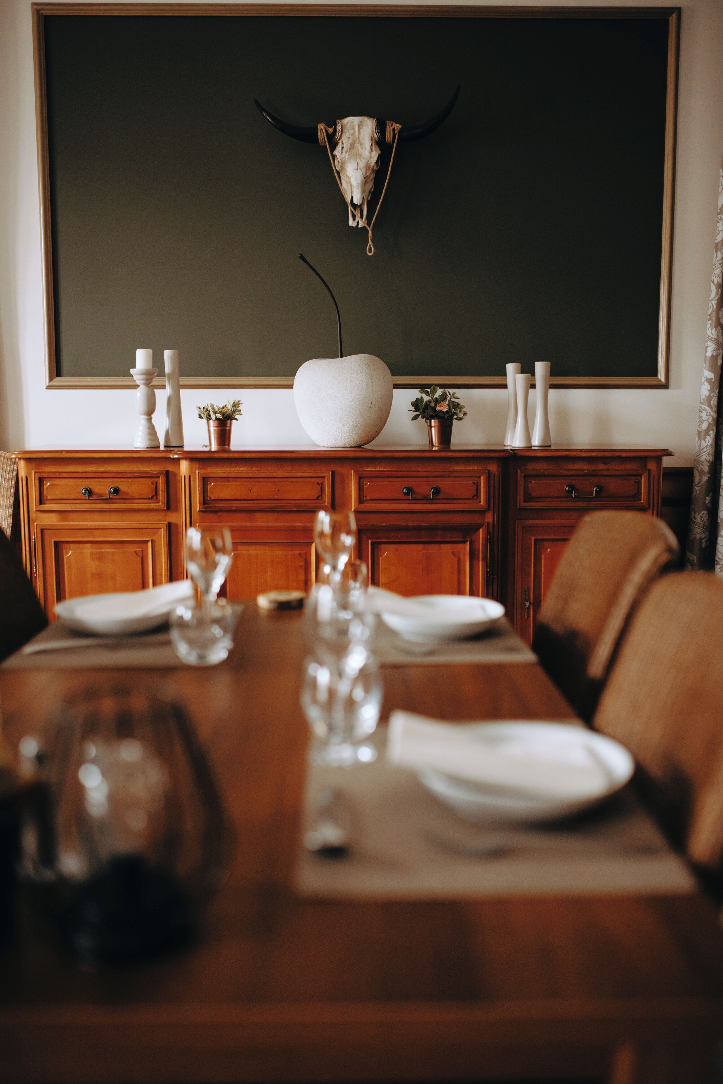 A dining table set with plates, glasses, and a vase.