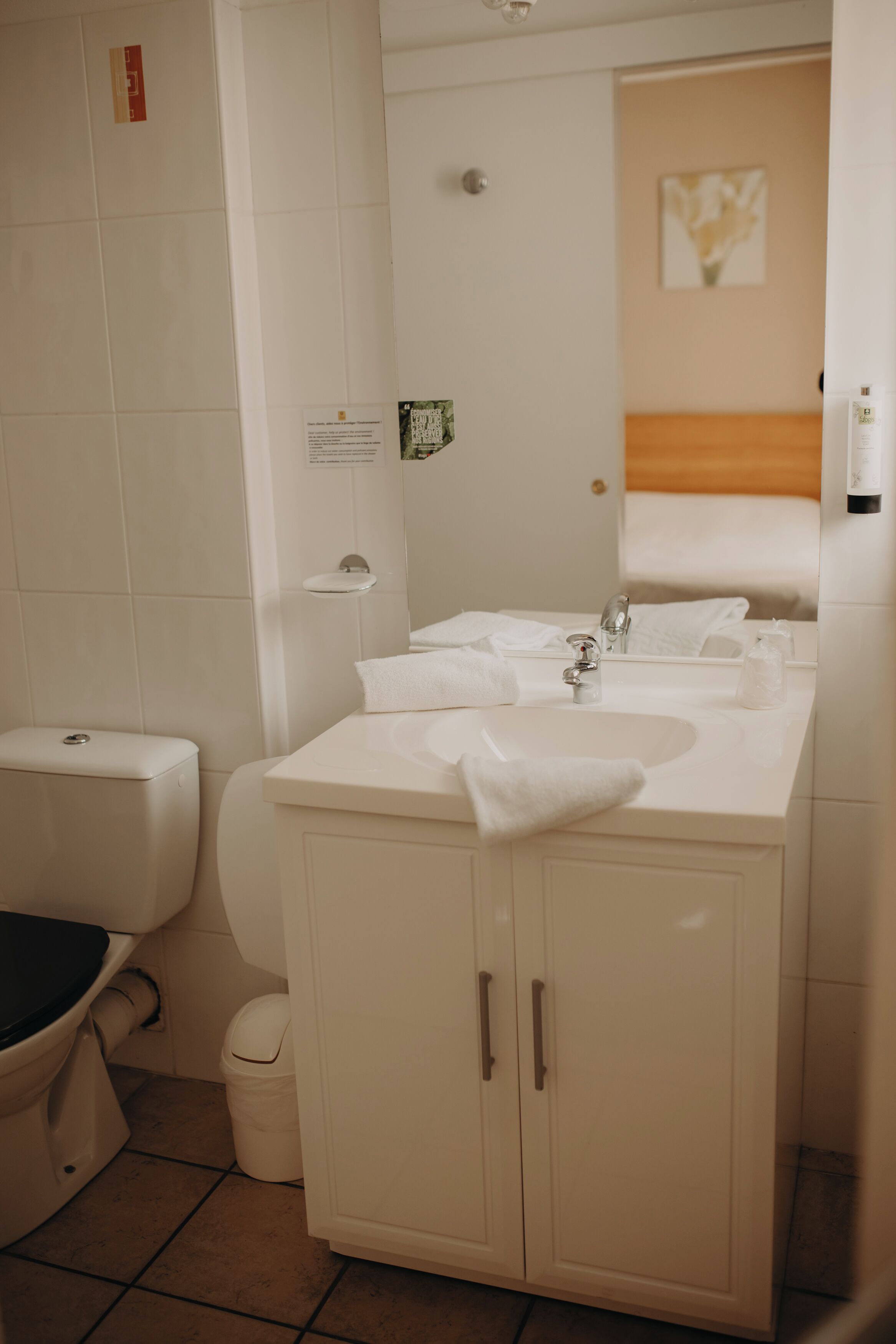 A bathroom with a toilet, sink, cabinet, and a mirror.