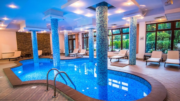 An indoor swimming pool with tiled columns, lounge chairs, and large windows. - Orbilux (Bansko)