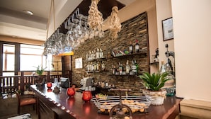 A bar area with a wooden counter, hanging wine glasses, and shelves with bottles. - Orbilux (Bansko)