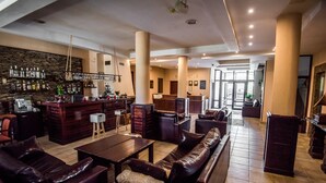 A spacious lobby with leather seating, a bar area with bottles and glasses, and a stone wall. - Orbilux (Bansko)