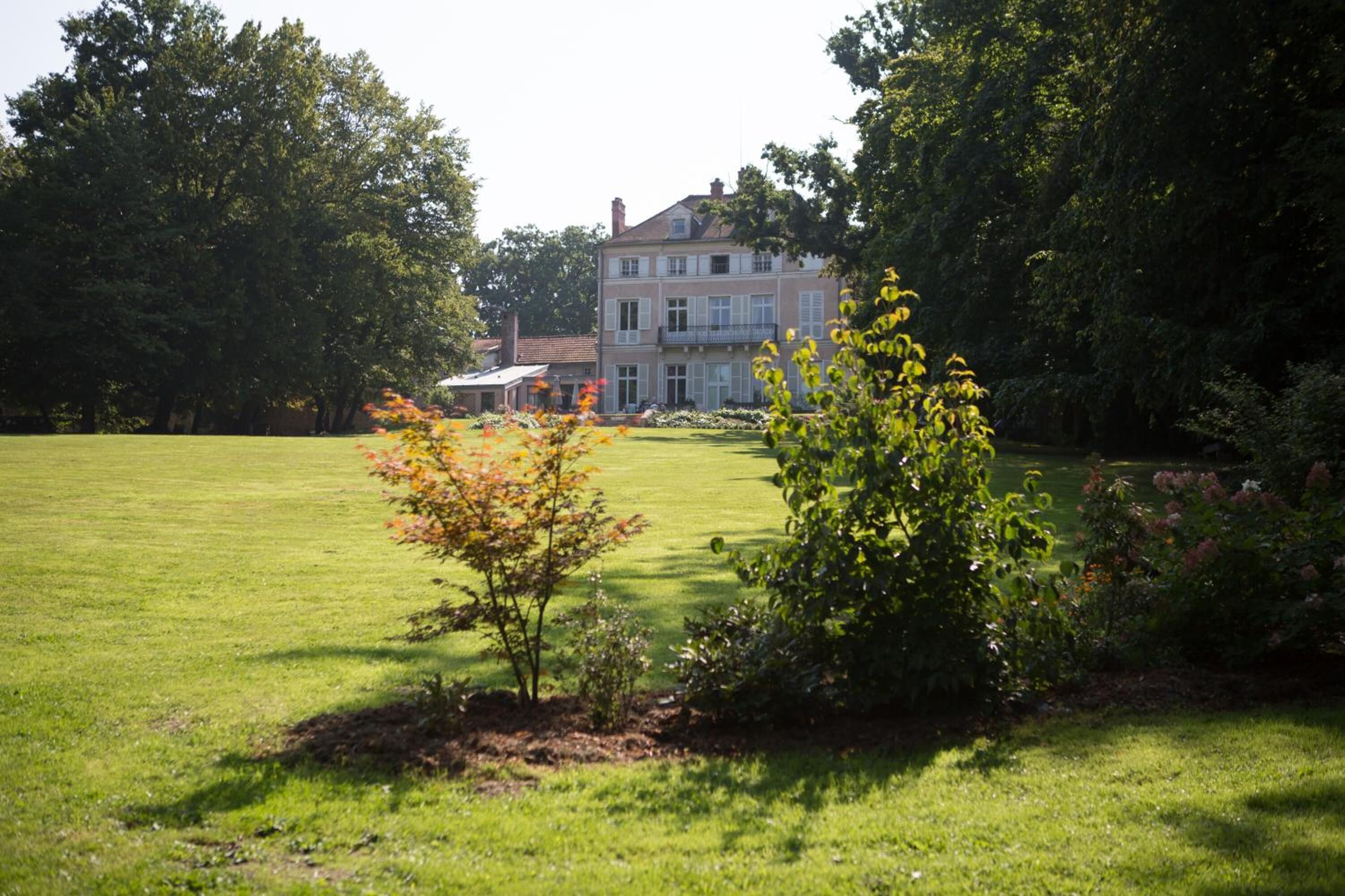 Une grande maison à deux étages, dotée d’une pelouse et d’un jardin bien entretenus à l’avant.