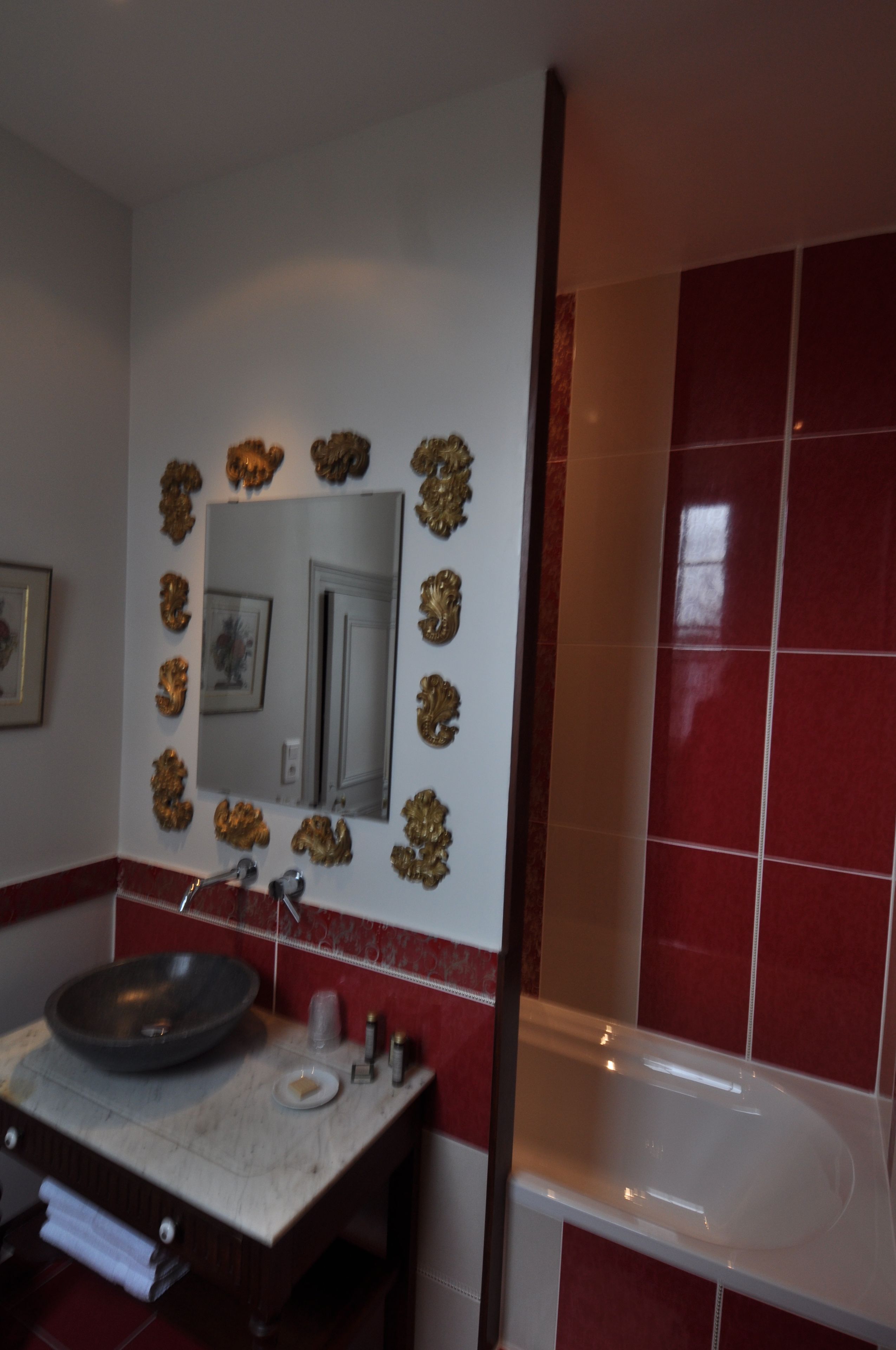 A bathroom with a sink, mirror, and red-tiled walls.