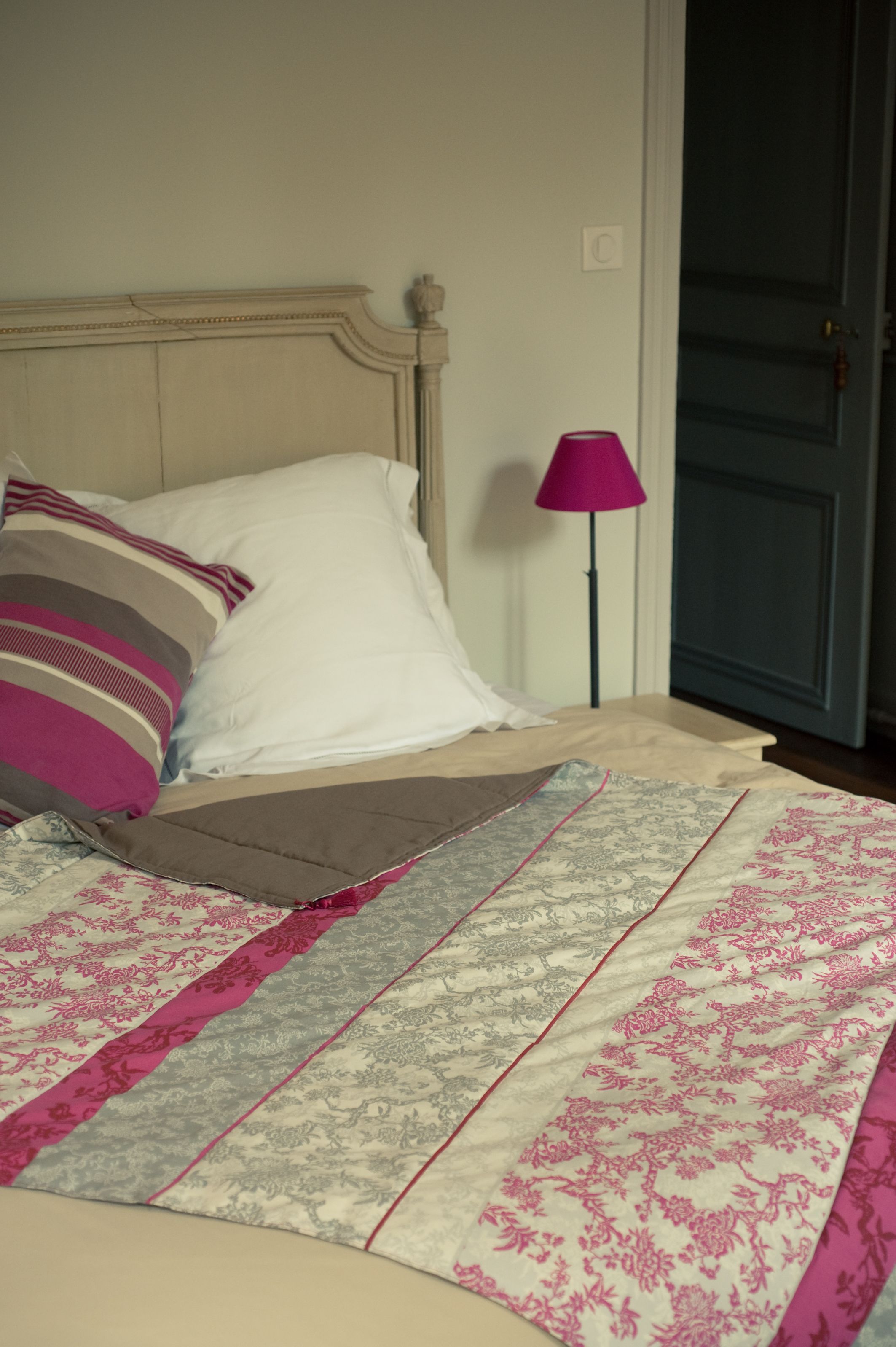 Una cama con una colcha estampada, una almohada blanca y una almohada a rayas.