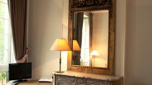 A room with a fireplace, a mirror, a lamp, a television, and a chair. - Le Château de la Vierge (Bures-sur-Yvette)