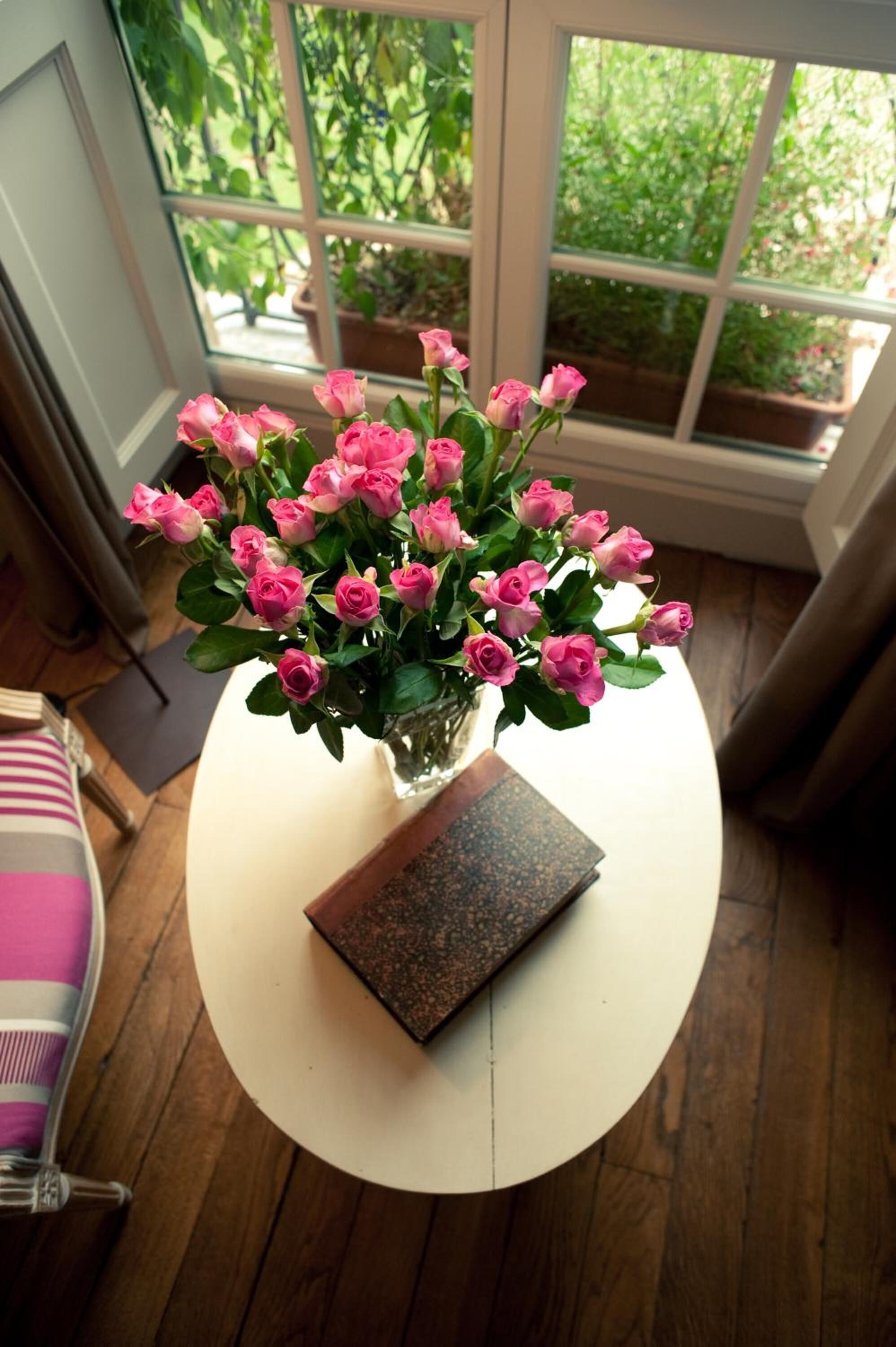 A table with a vase of pink roses and a book.