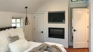 A bedroom with a large bed, a fireplace, and a TV mounted on the wall. - Casablanca (Cape May)