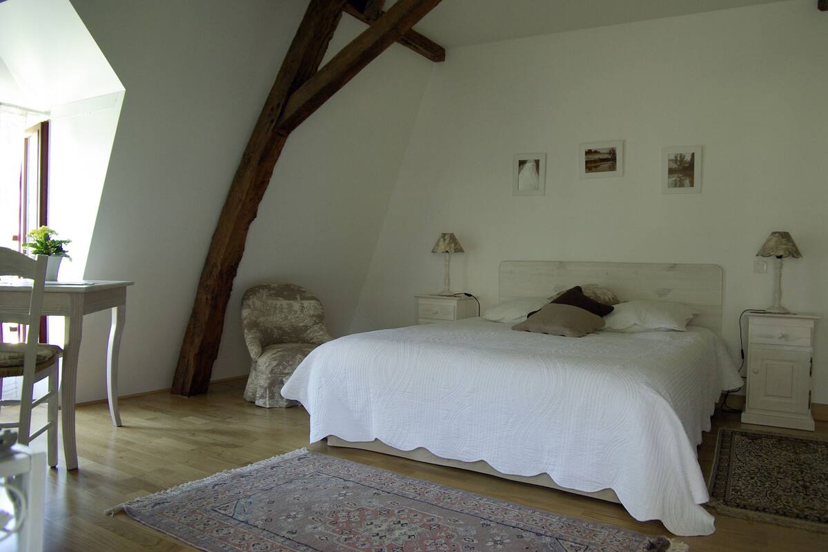 A bedroom with a bed, nightstands, a chair, and a desk.