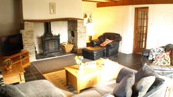 A cozy living room with a stone fireplace, a leather armchair, a sofa, and a television.