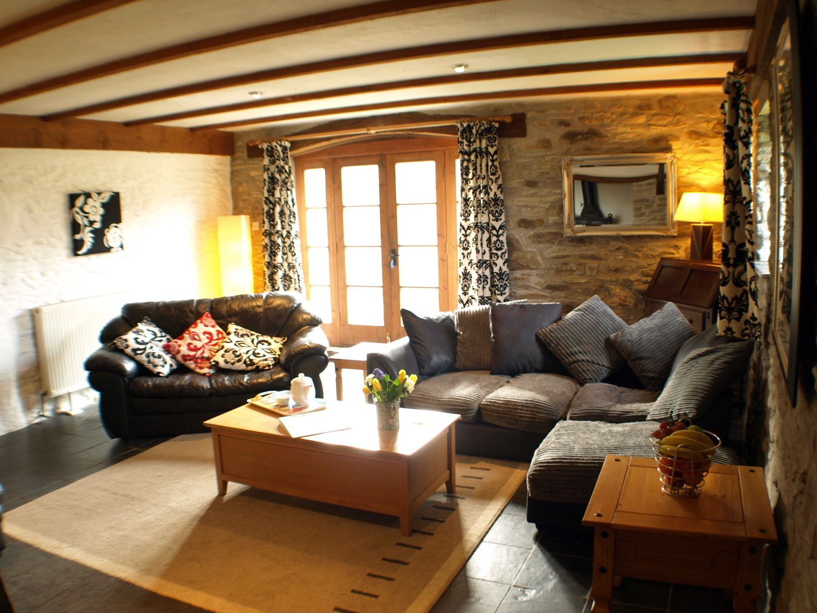 A cozy living room with a fireplace, a sofa, a coffee table, and a small side table with a fruit bowl.