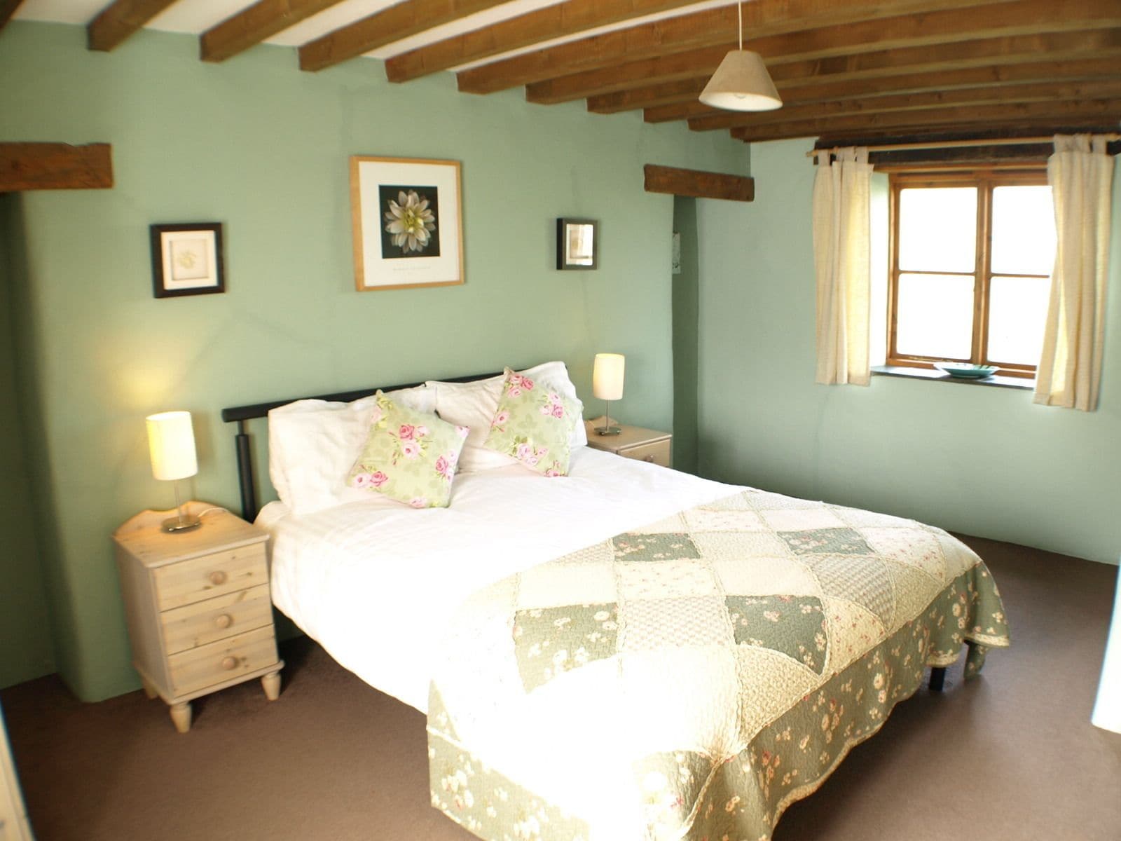 A bedroom with a bed, a nightstand, a dresser, and a window with curtains.