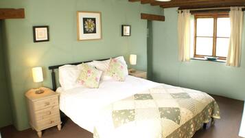 A bedroom with a bed, a nightstand, a dresser, and a window with curtains.