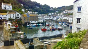 A harbor with boats docked, stone walls, and buildings along the water. - Polean Farm Cottages (Looe)