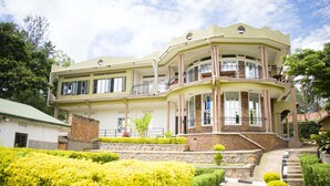 Un edificio de varios pisos con balcones, fachada de piedra y un jardín ajardinado.