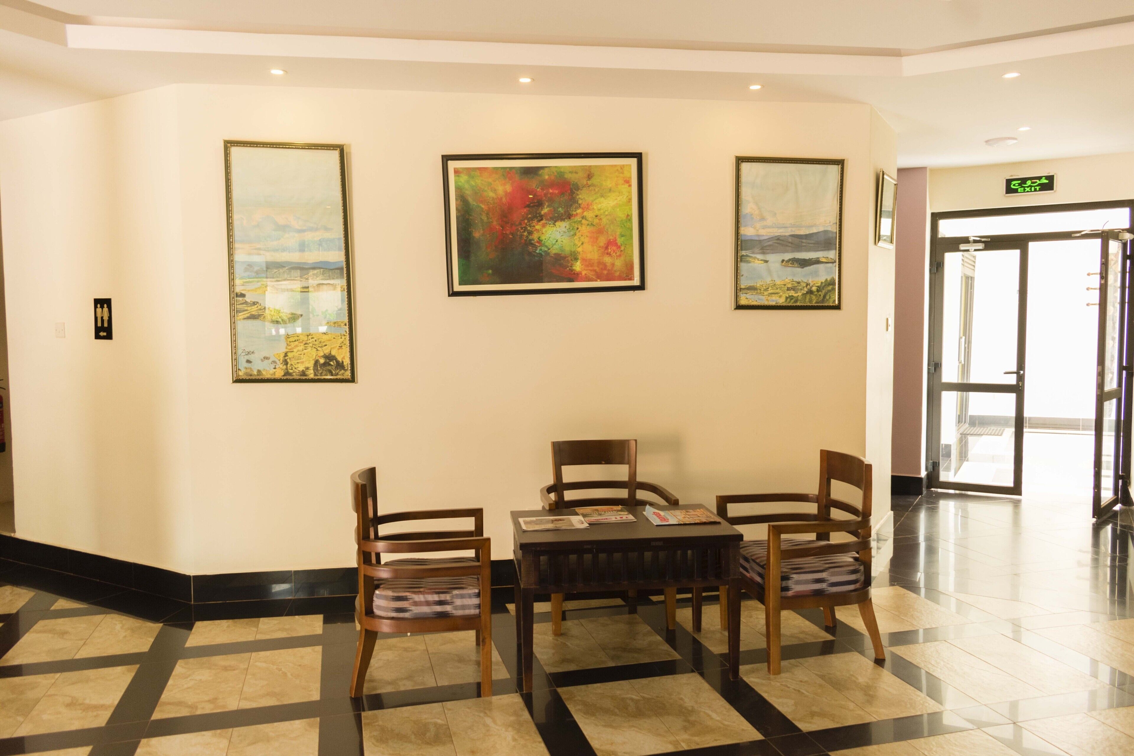 A lobby with a reception desk, a table with chairs, and three framed artworks on the wall.